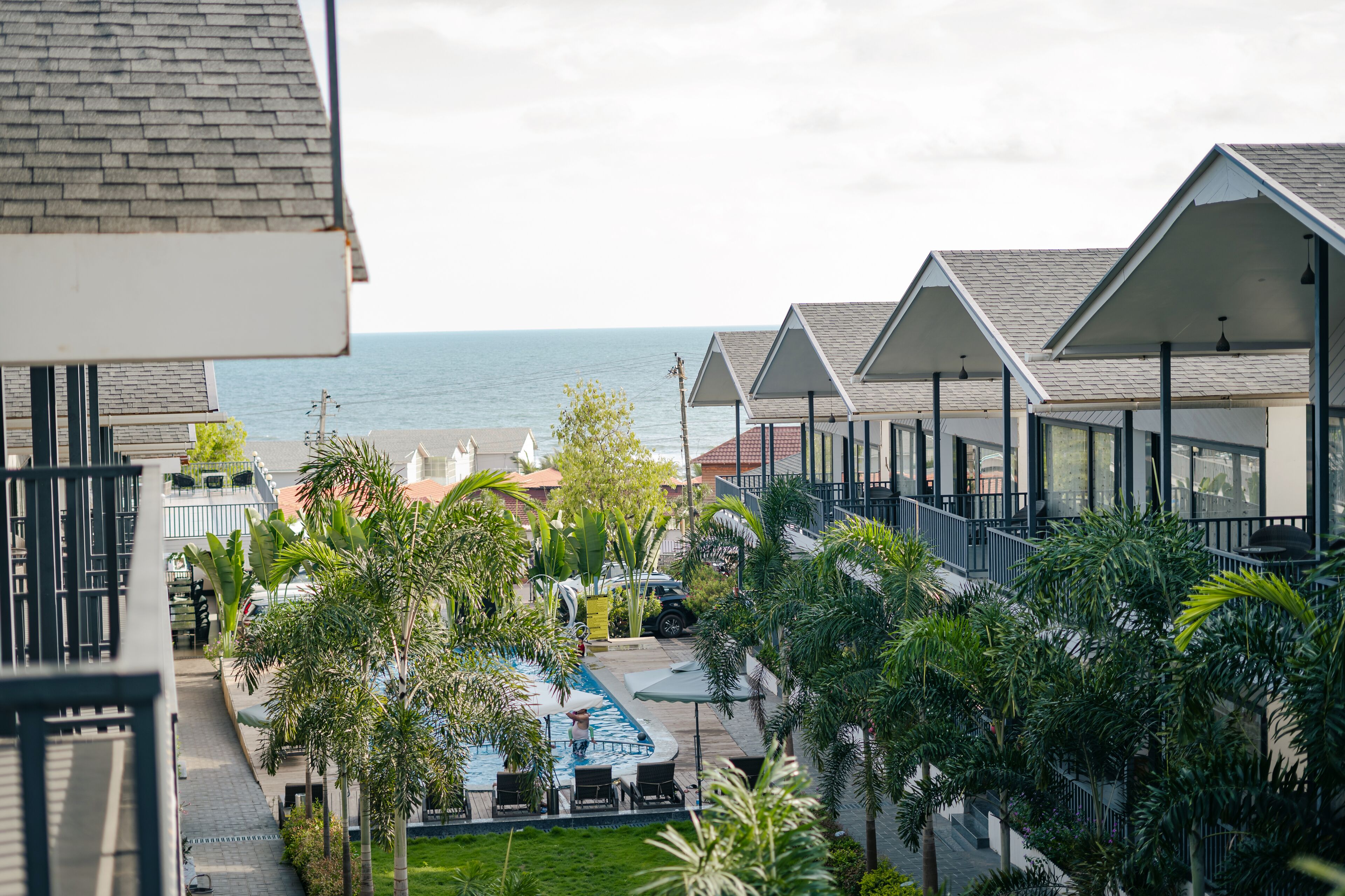 A resort with a pool, palm trees, and a view of the ocean.