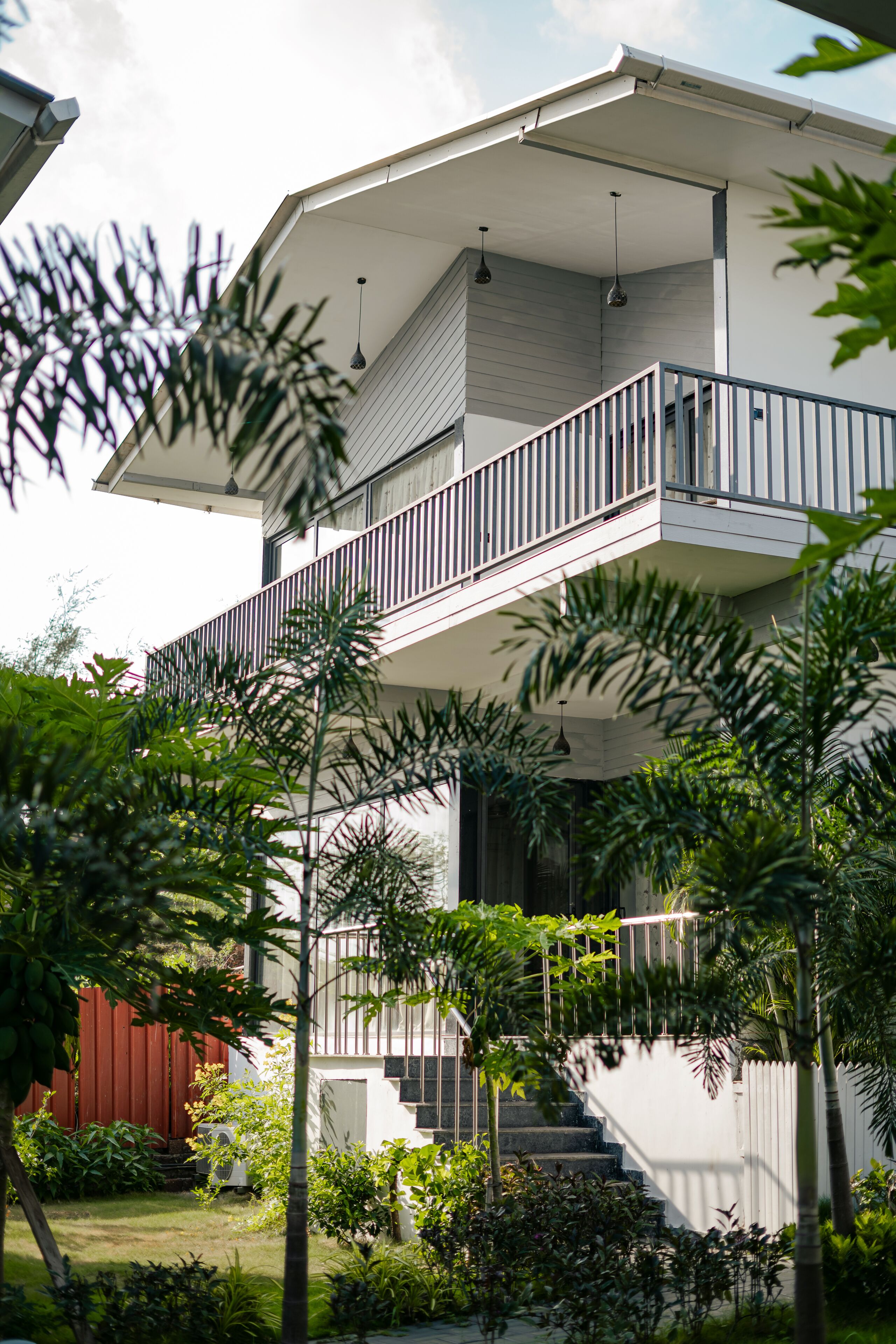 Una moderna casa a due piani con un balcone, immersa nel verde.