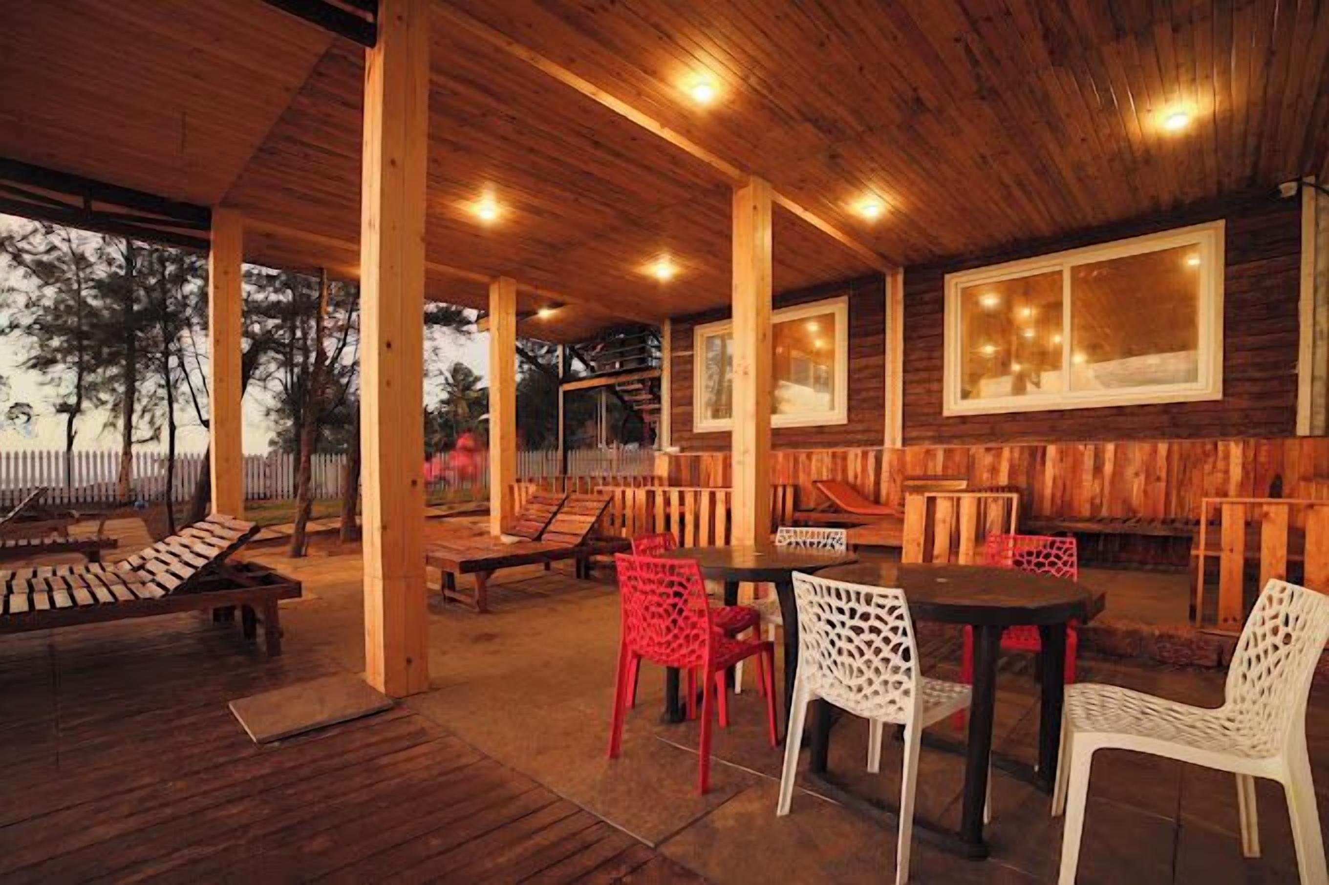 Une terrasse extérieure couverte, dotée d’un plancher en bois, d’une table avec des chaises et d’une clôture en bois en arrière-plan.