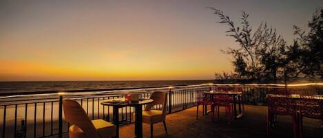 Un restaurant en bord de mer avec une terrasse, une vue sur l’océan et une rambarde.