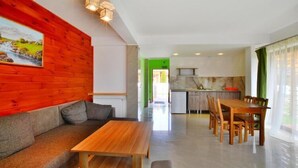 A modern living room with a wooden sofa, a wooden table, and a green wall. - Holiday home with a private garden (Sarbinowo)