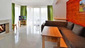 Un salon moderne avec un canapé, une table basse en bois, un téléviseur posé sur un meuble et une cheminée.