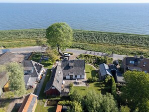 An aerial view of a residential area with houses, a road, and a body of water in the background. - historic cottage in scenic Dutch landscape at IJsselmeer (Andijk)