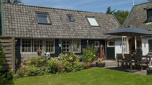 A traditional house with a tiled roof, a front porch, and a garden area with potted plants and flowers. - historic cottage in scenic Dutch landscape at IJsselmeer (Andijk)