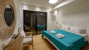 A hotel room with a bed, a desk, a chair, a mirror, and a sliding door leading to a balcony. - Greek Zen villa - stunning sea view -top of the hill in Athens Riviera (PWV6+C39 Saronida, Greece)