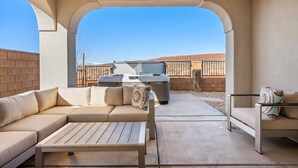 An outdoor patio with a beige sofa, a wooden table, and a hot tub. - TNT Sun Adventures: Hot Tub, Arcade, Air Hockey (Washington)