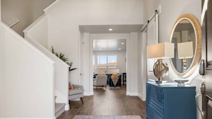 A hallway with a staircase, a blue vanity with a mirror, and a dining area in the background. - TNT Sun Adventures: Hot Tub, Arcade, Air Hockey (Washington)