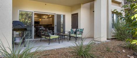 A patio area with outdoor seating, a grill, and a view of the building's interior.