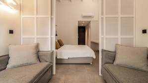 A modern bedroom with a bed, two sofas, and a walk-in closet. - New Beach Hotel (Zakynthos)