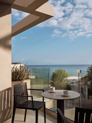 A balcony with a table and chairs, overlooking a coastal view. - New Beach Hotel (Zakynthos)