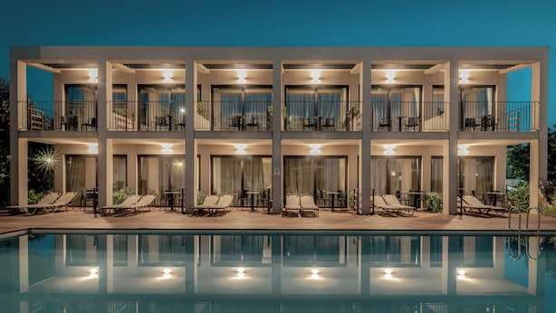 A modern hotel with a pool, multiple balconies, and outdoor seating areas. - New Beach Hotel (Zakynthos)
