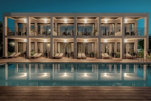 A modern hotel with a pool, multiple balconies, and outdoor seating areas. - New Beach Hotel (Zakynthos)