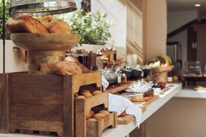 A breakfast buffet with bread, pastries, and fruits.