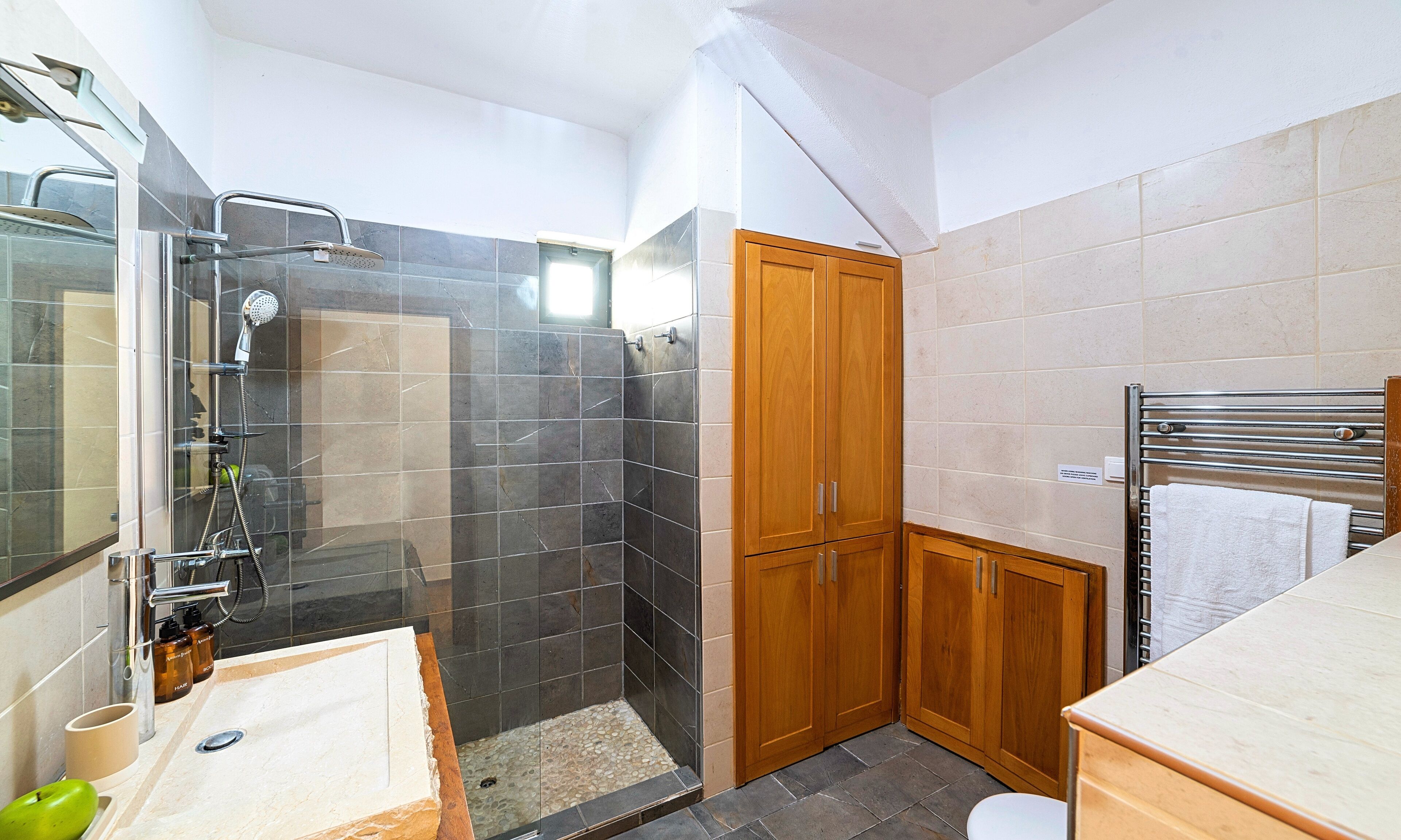 Une salle de bain moderne avec une douche à parois de verre, des meubles en bois et un sol carrelé.