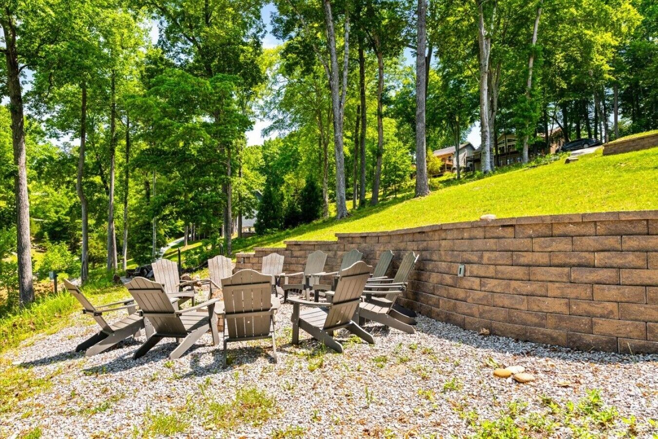 Uma área de pátio com cadeiras Adirondack, uma parede de tijolos e um gramado suave.
