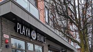 A storefront with a sign reading "PLAYA BOWLS" and a menu board outside advertising smoothies and bowls. - Luxury 1 Bedroom Downtown Traverse City (Traverse City)