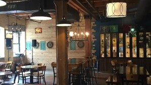 A restaurant interior with wooden walls, hanging pendant lights, and a bar area with shelves. - Luxury 1 Bedroom Downtown Traverse City (Traverse City)