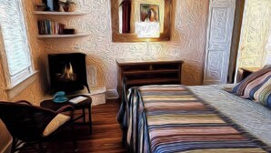 A cozy room with a fireplace, a bed, a chair, and a bookshelf. - Barkley-Hayward Cottage (Little Rock)