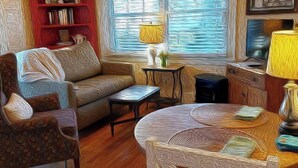 A living room with a sofa, coffee table, and a bookshelf. - Barkley-Hayward Cottage (Little Rock)