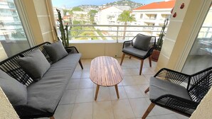 A balcony with a sofa, two chairs, and a small table. - Luxury 3 bedroom apartment (Cannes)