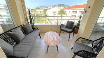 A balcony with a sofa, two chairs, and a small table.