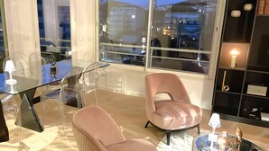 A modern living room with a glass table, two leather chairs, a glass coffee table, and a bookshelf. - Luxury 3 bedroom apartment (Cannes)