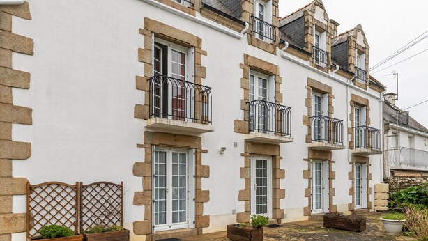 Une rangée de bâtiments blancs agrémentés de détails en pierre, avec de nombreuses fenêtres et des balcons.
