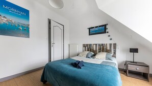 Une chambre avec un lit, une table de chevet, une affiche et une vue sur la mer.