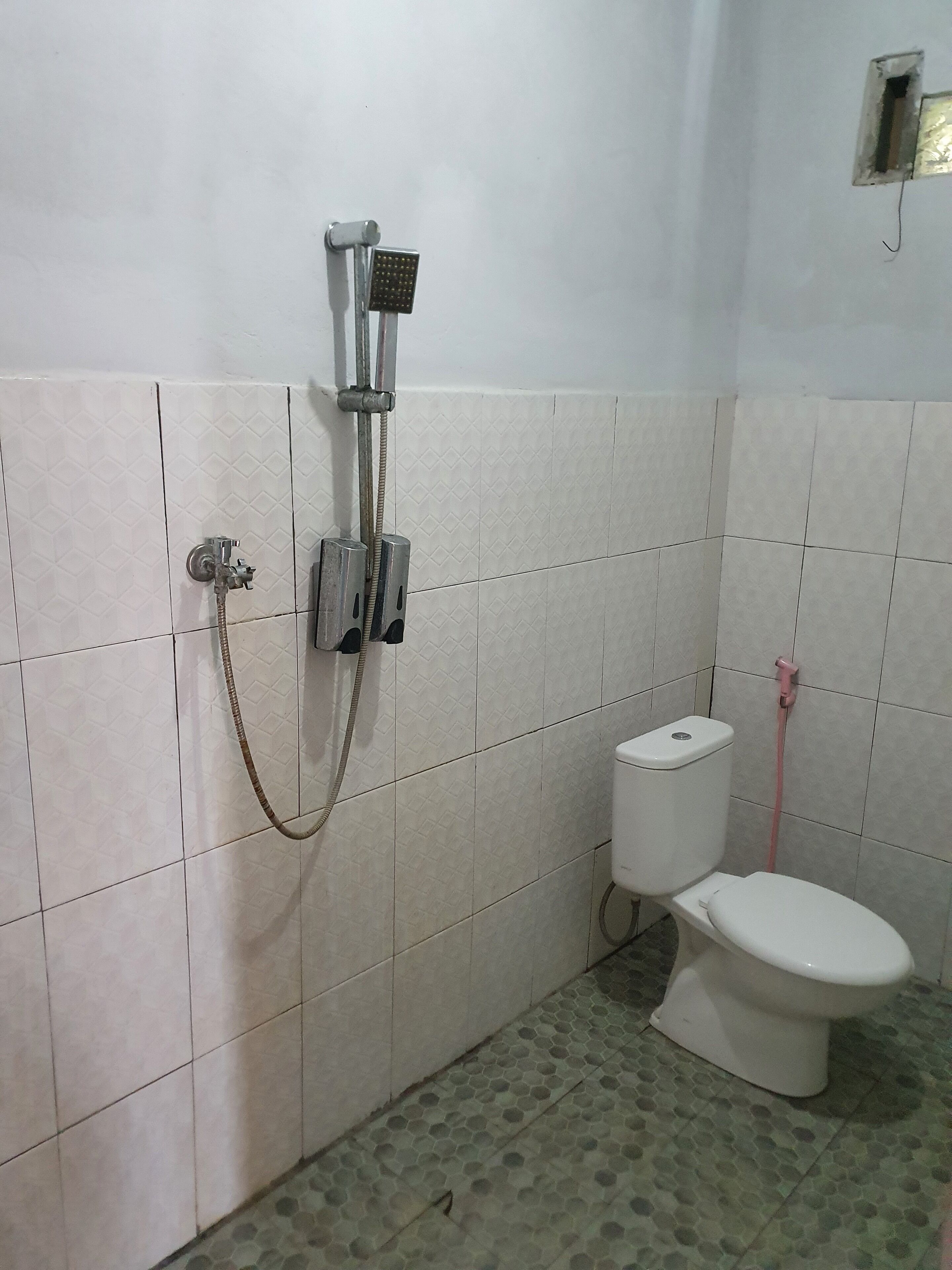 Un baño con ducha, inodoro y paredes de azulejos.