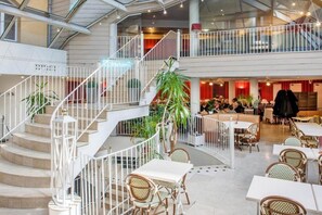 A spacious indoor area with a central staircase, multiple seating areas, and a dining section. - Hotel Saint Sauveur (Lourdes)