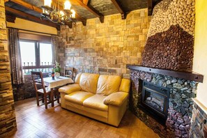 Cozy space with a fireplace, leather sofa, and dining area.