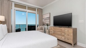 A hotel room with a large bed, a flat-screen TV, a wooden dresser, and a balcony with a view of the sea. - Phoenix Gulf Tower 1801 by Brett/Robinson (Orange Beach)