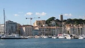 A marina with boats docked, buildings in the background, and a crane. - Villa Saint Henri (Cannes)