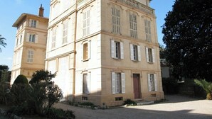 A multi-story building with a symmetrical facade, large windows with shutters, and a central entrance. - Villa Saint Henri (Cannes)