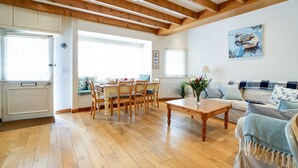 Un vaste espace de vie doté de planchers en bois, d’une table à manger et d’un canapé.