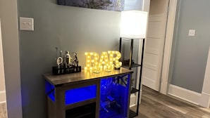 A modern living room with a dark wood console table featuring a blue-lit compartment, a wall-mounted painting, and a white lamp.