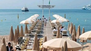 A beachside area with rows of sun loungers and umbrellas, a sign reading "Carlton Intercontinental", and a yacht in the background.
