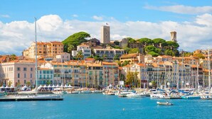 A coastal town with historic buildings, a marina with boats, and a prominent tower.