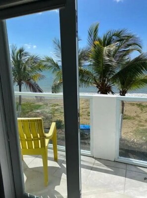 Relax on the balcony with a view of the ocean and palm trees.