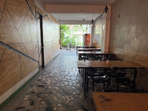 A restaurant interior with tiled flooring, wooden tables, and black chairs. - Hotel Greenview Medellin (Medellín)