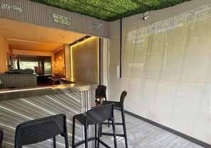 A bar area with a counter and two chairs, a projection screen on the wall, and a green artificial grass ceiling. - Hotel Greenview Medellin (Medellín)