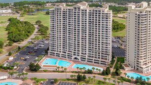 A high-rise hotel with multiple balconies, a swimming pool, and a view of the ocean. - Ariel Dunes II 1610 - Corner Unit, Gulf Views, Pool, Fitness, Onsite Dining! (Miramar Beach)