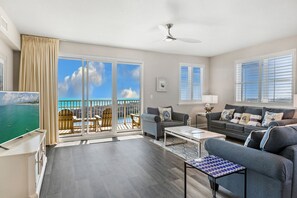 Relax in this stylish living room with a large flat-screen TV, comfortable seating area, and sliding glass door to a balcony with ocean views.