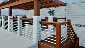 Ein überdachter Außenbereich mit einer Pergola, weißen Geländern und einem Schild mit der Aufschrift 'SALTY AIR DR'.