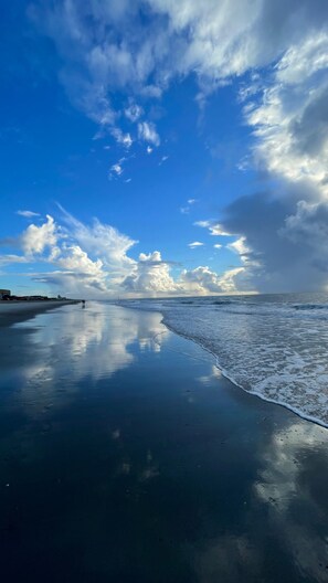 A beach with wet sand reflecting the sky and clouds. - Oceanview NEW Home with Amazing Rooftop and Rec Room! Under 3 min walk 2 beach! (Carolina Beach)