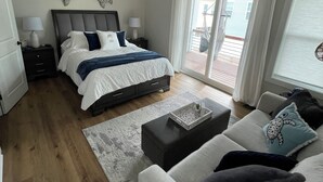 Ein modernes Schlafzimmer mit Bett, Deckenventilator, Nachttisch und Blick ins Freie.