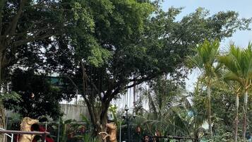 Un sendero en un jardín con una estatua de un caballo, una pareja y abundante vegetación.