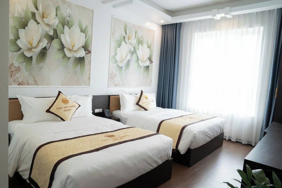A hotel room with two beds, a desk, and large floral artwork on the walls.