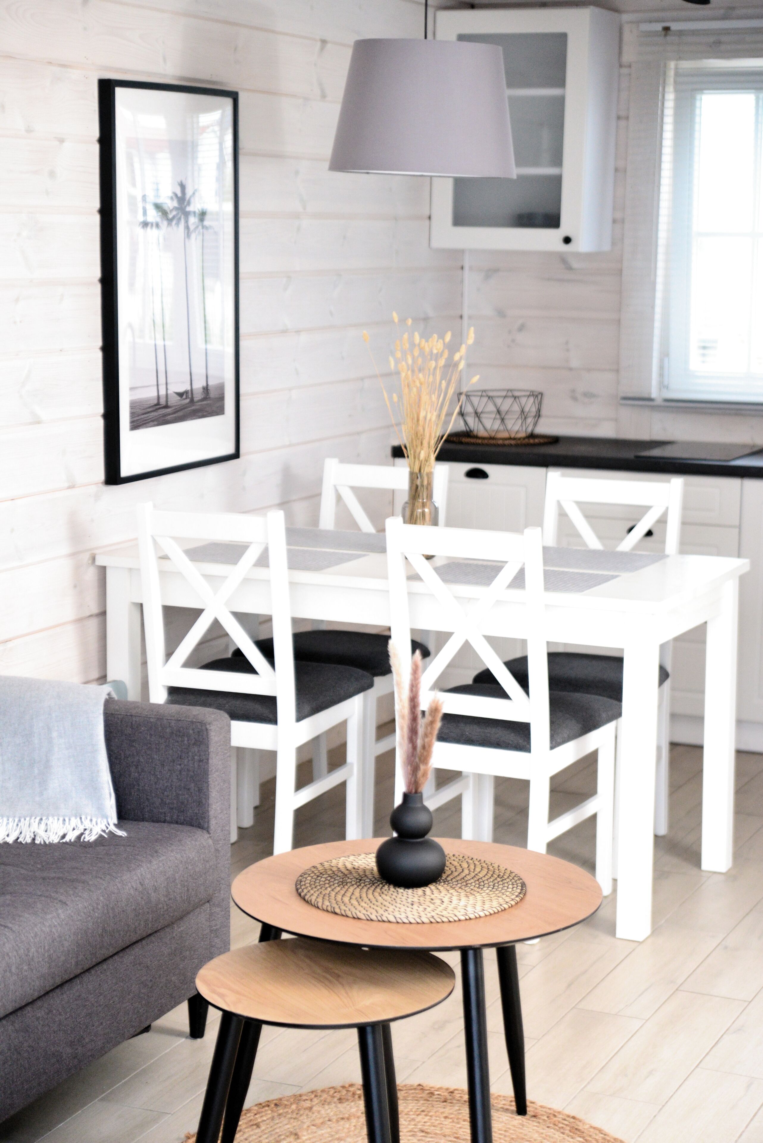 A modern kitchen with white cabinetry, a dining table with chairs, and a small round table with a vase.