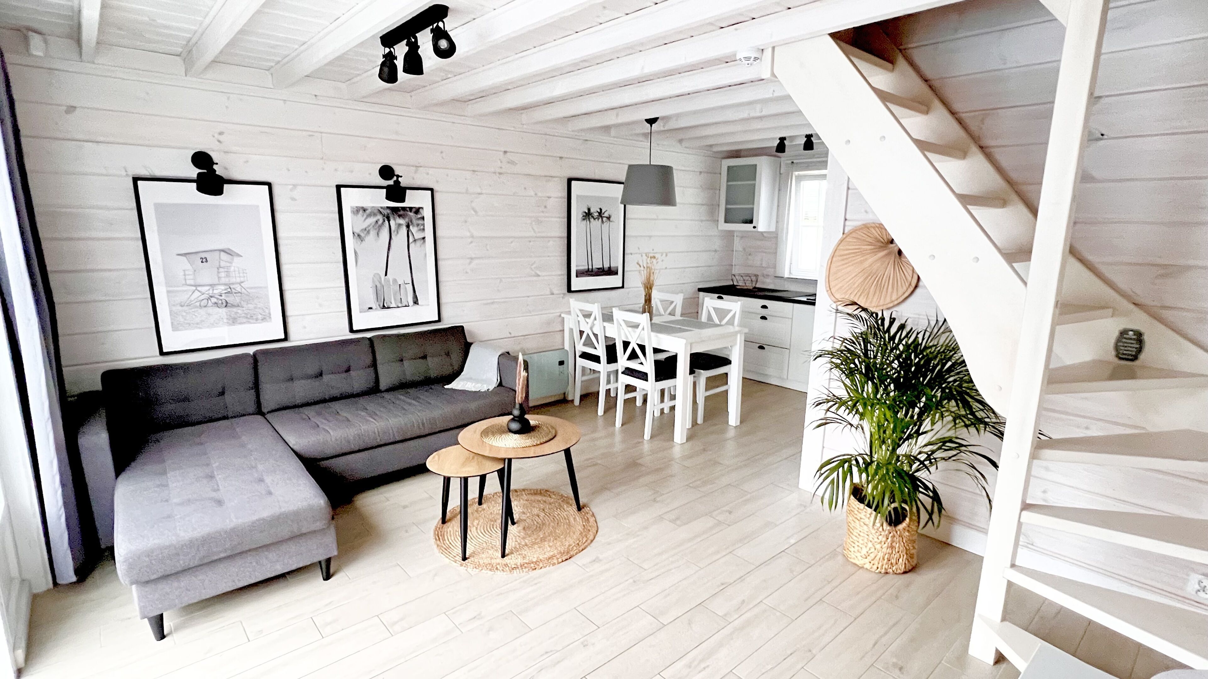 Un salon moderne avec un canapé gris, une petite table ronde et un escalier menant à un espace cuisine.